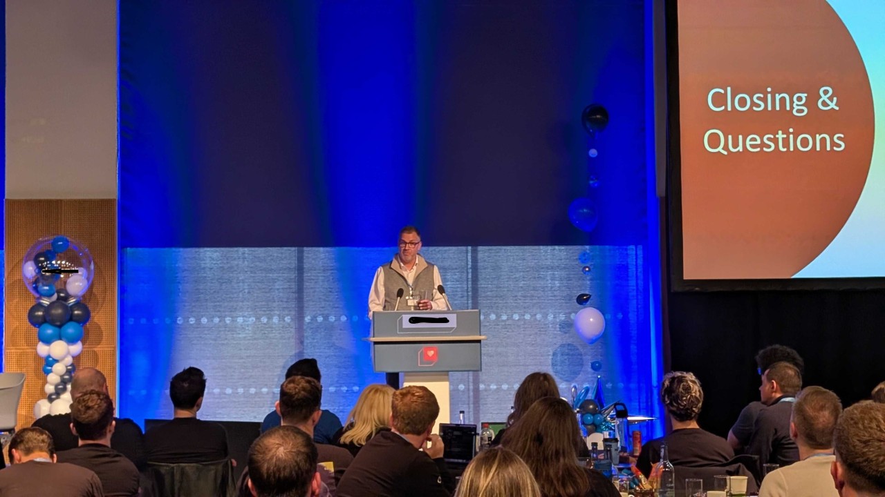 Bram Weerts speaking on stage during the closing questions at a technology customer event.